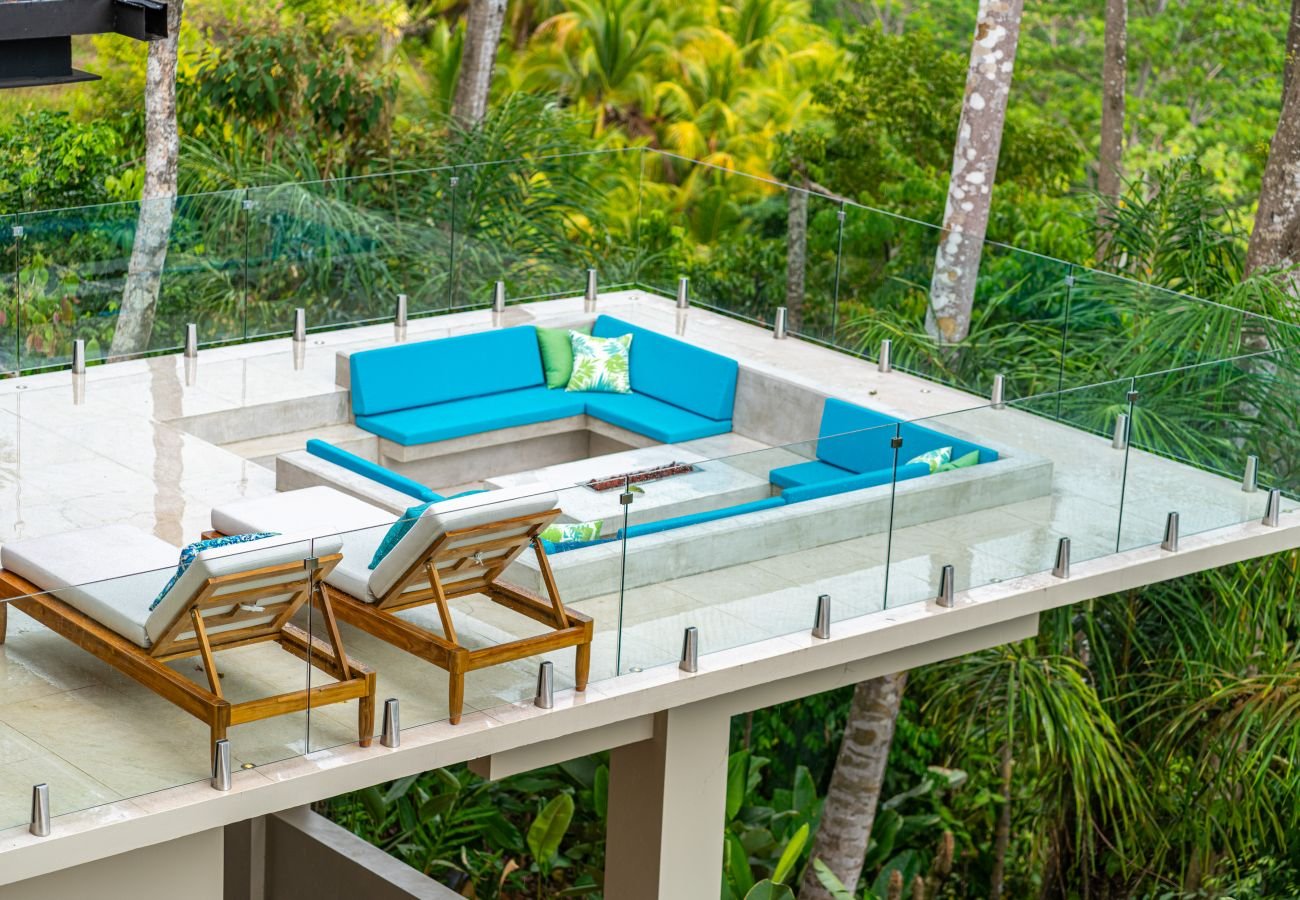 The teak dining table and woven chairs, with the garden beyond the glass