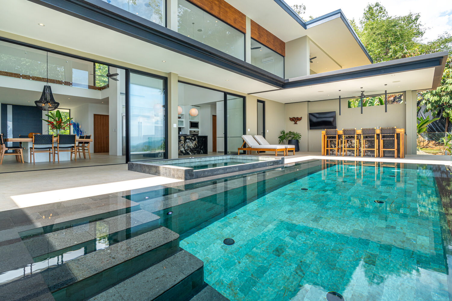 The infinity pool with green stone tile and jacuzzi, open to the living spaces