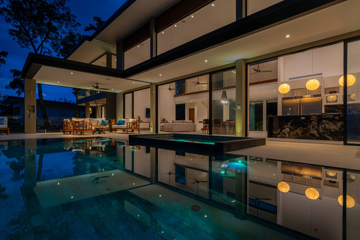 The pool and villa at blue hour, glowing against the evening sky