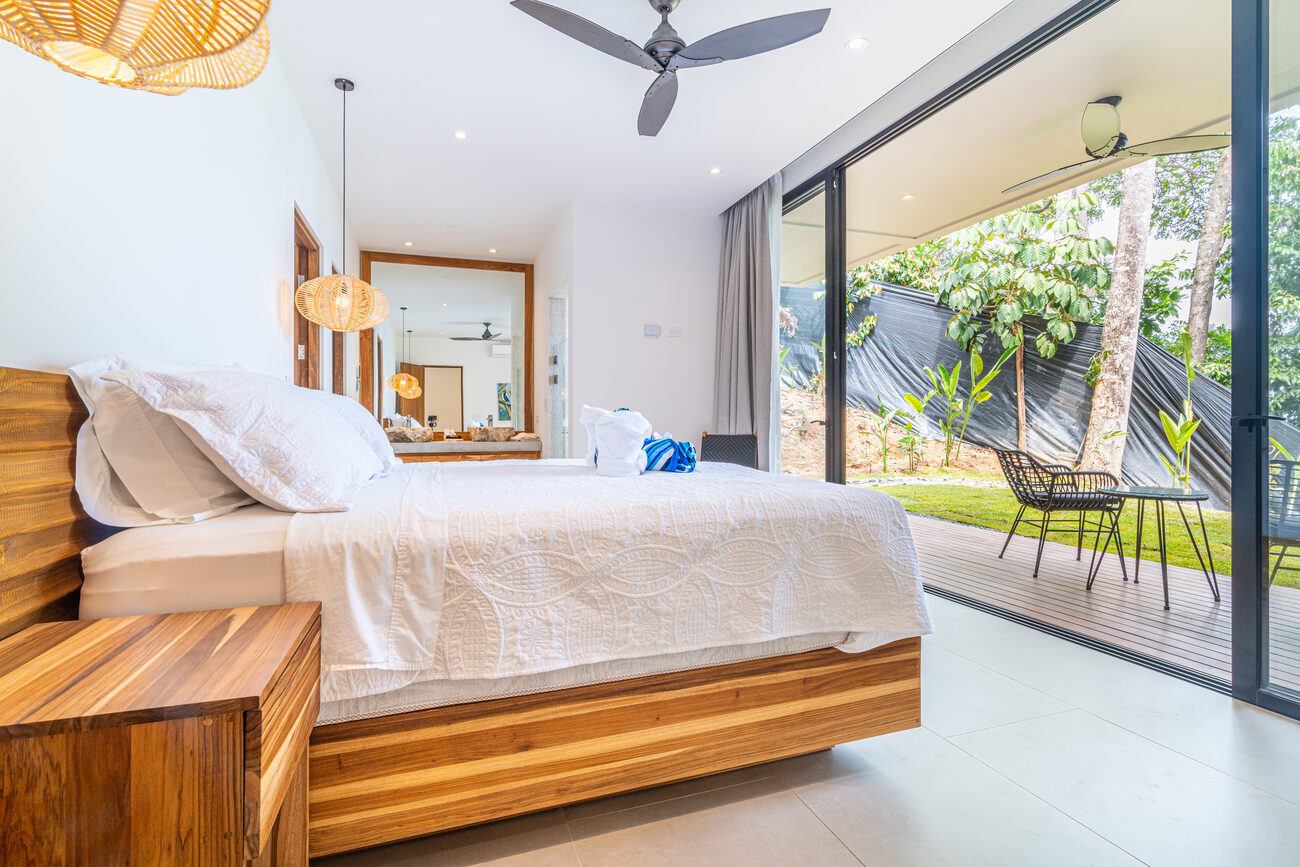 A king suite opening through full-height glass to a private garden terrace