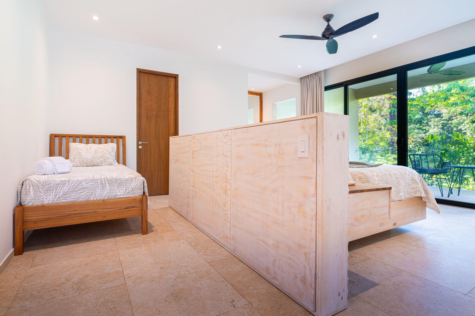 Jungle-view bedroom — the in-room single (twin) bed and the king, separated by a half-height wood divider