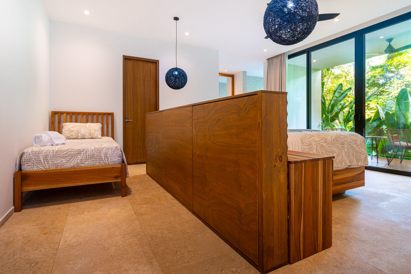 The second jungle-view bedroom — twin bed beside the king, behind its wood divider