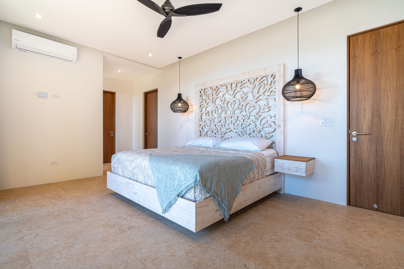 Ocean-view king suite with carved headboard and pendant lighting